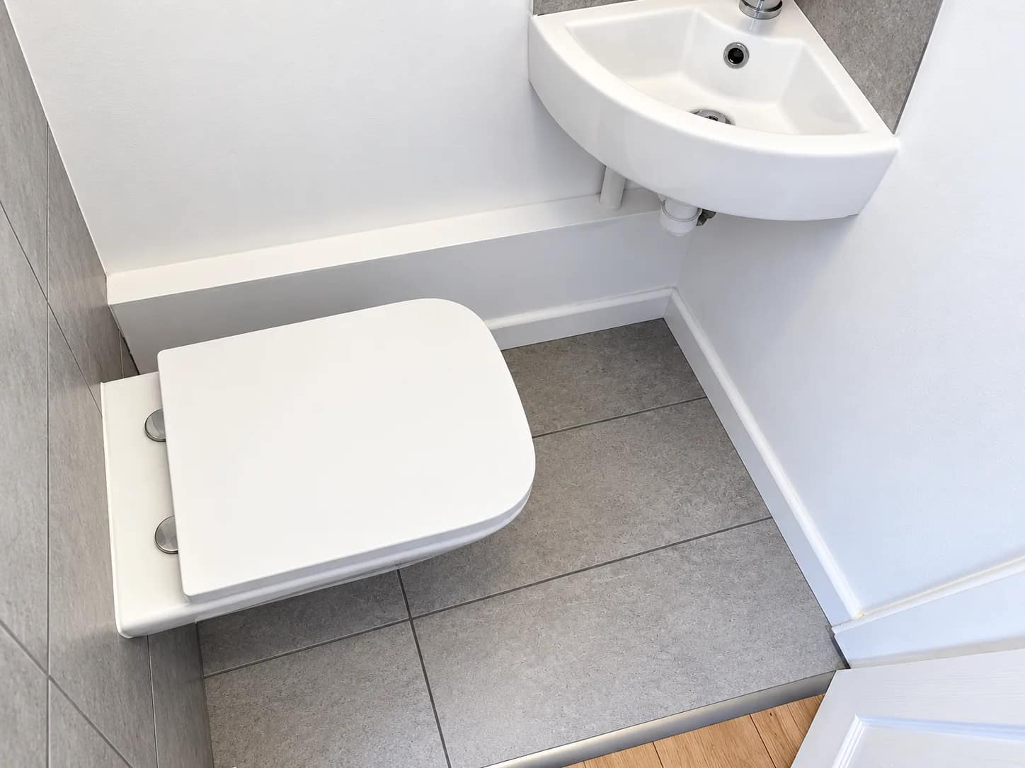 A compact bathroom with the toilet, basin and tiled floor left clean