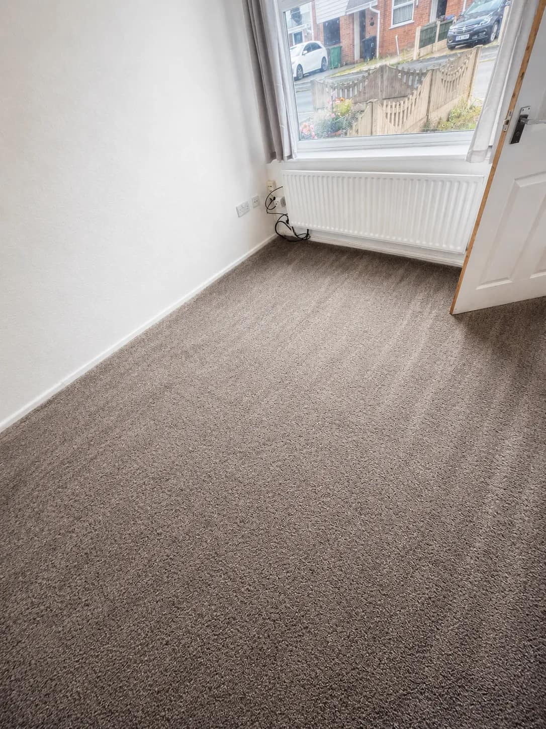 A freshly cleaned carpet groomed into even lines in an empty room.